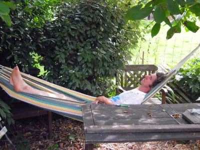 a man laying in a hammock on a bench at Holiday home Brokantie in Pamel