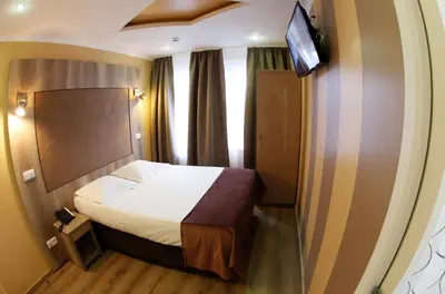 a small bedroom with a bed and a tv on a wall at Hotel Phenix in Brussels