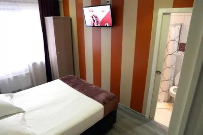 a bedroom with a bed and a tv on the wall at Hotel Phenix in Brussels
