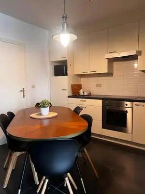 a kitchen with a wooden table and black chairs at Anna Place in Ghent