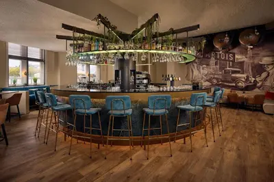a bar with blue bar stools in a room at Van der Valk Hotel Mechelen in Mechelen