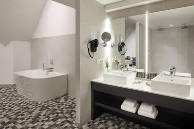 a bathroom with two sinks and a mirror at Van der Valk Hotel Mechelen in Mechelen
