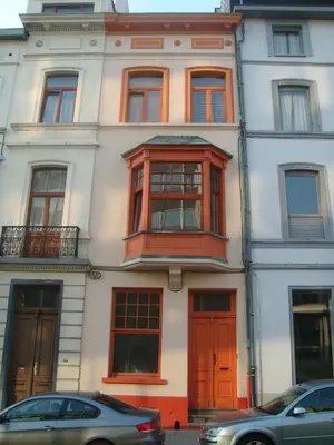 a tall white building with red doors and windows at Appart-hôtel Maison de la Lune - petite Auberge d'Etterbeek in Brussels