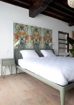 a bedroom with a white bed with a floral wall at The Greenhouse in Antwerp