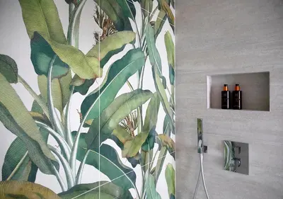a bathroom with a tropical wallpaper with three bottles of wine at The Greenhouse in Antwerp