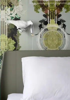 a bed with a white pillow and a chandelier at The Greenhouse in Antwerp