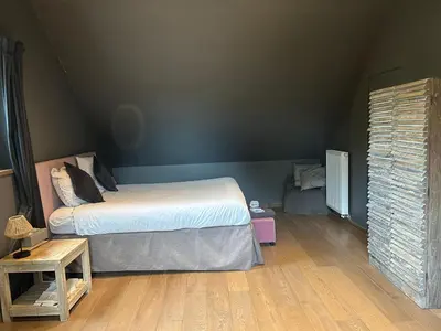 a bedroom with a bed and a wooden floor at B&B Des Heures Claires in Lasne