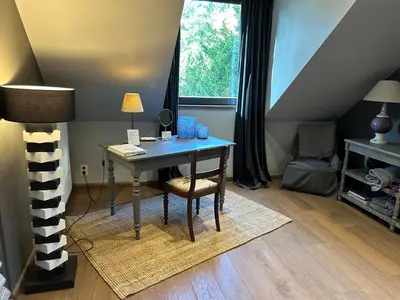a desk in a room with a table and a window at B&B Des Heures Claires in Lasne