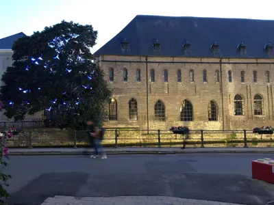 a person walking in front of a large building at studio medieval city center at river de Leie in Ghent