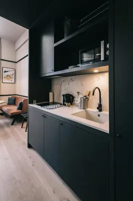 a kitchen with black cabinets and a white sink at Getaway Gent in Ghent