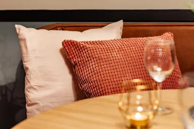 a glass of wine sitting on a table with a pillow at Getaway Gent in Ghent
