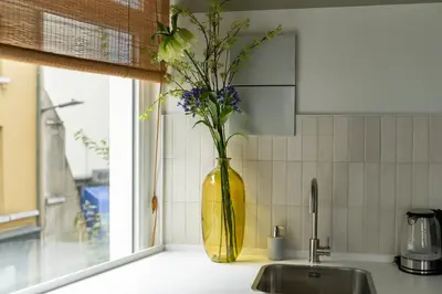 a yellow vase with flowers in it on a kitchen counter at SHWAY - The Black Pants in Antwerp