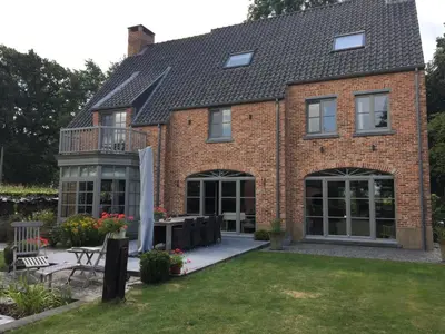 a brick house with a conservatory and a patio at Bed and Breakfast Bobilou in Kalmthout