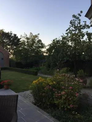 a garden with flowers and trees and a house at Bed and Breakfast Bobilou in Kalmthout