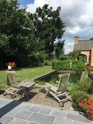 two chairs and a table next to a pond at Bed and Breakfast Bobilou in Kalmthout