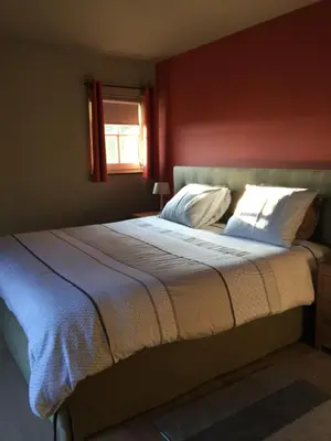 a bed in a bedroom with a red wall at Bed and Breakfast Bobilou in Kalmthout