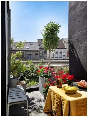 a patio with a table and flowers on a balcony at Studio Spiegelhof in Ghent