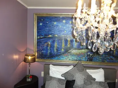 a painting hanging above a bed with a chandelier at Art Of Dreams Deluxe 4 stars in Laakdal