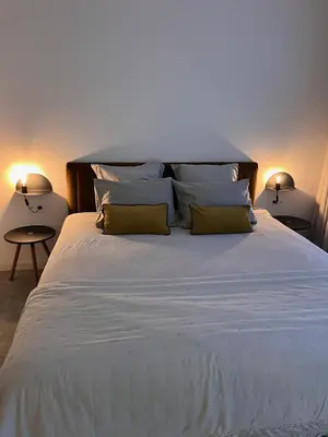 a large bed with white sheets and yellow pillows at B&B Achilles in Ghent