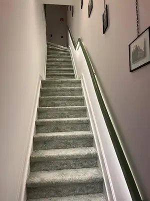 a staircase with grey carpeted stairs with green railings at B&B Achilles in Ghent
