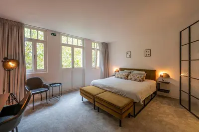 a bedroom with a bed and a chair and windows at B&B Achilles in Ghent