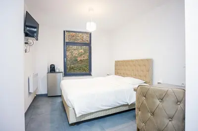 a white bedroom with a bed and a window at Résidence la floraison in Brussels