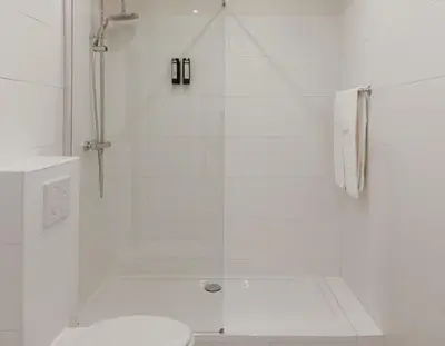 a white bathroom with a shower and a toilet at La Lys Rooms & Suites in Ghent