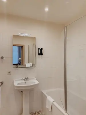 a white bathroom with a sink and a shower at La Lys Rooms & Suites in Ghent