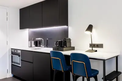 a kitchen with black cabinets and blue chairs at Residence Inn by Marriott Ghent in Ghent