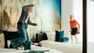 two children jumping on a bed in a room at Residence Inn by Marriott Ghent in Ghent