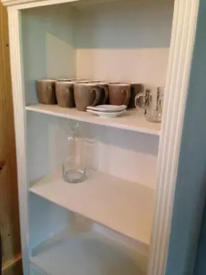 a shelf with cups and plates and a vase on it at Vakantiewoning De Kleine Duinberg - Chalet Nr 11 in Retie