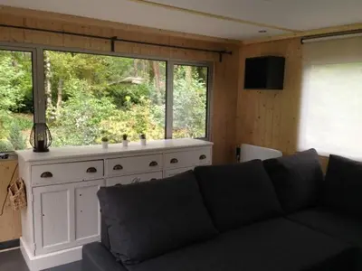 a living room with a couch and a large window at Vakantiewoning De Kleine Duinberg - Chalet Nr 11 in Retie