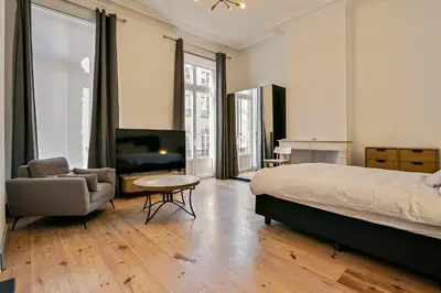 a bedroom with a bed and a chair and a television at Fish Market B&B in Brussels