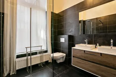 a bathroom with two sinks and a toilet and a window at Fish Market B&B in Brussels