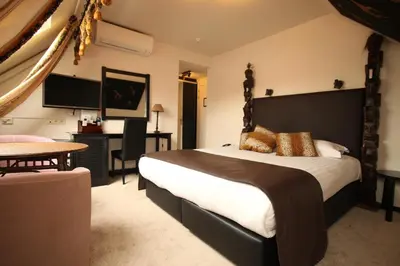 a bedroom with a large bed and a desk at Hotel La Roseraie in Wemmel