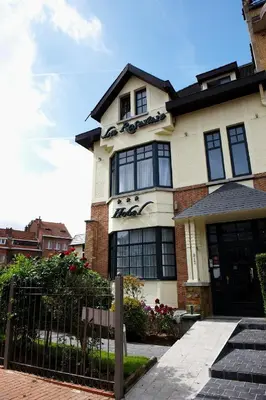 a white house with black windows and a fence at Hotel La Roseraie in Wemmel