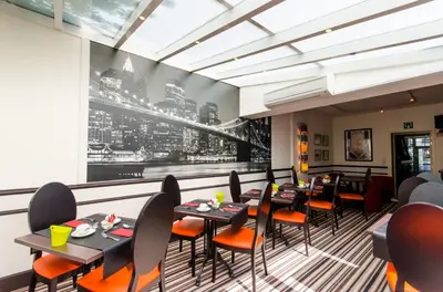 a restaurant with tables and chairs and a large window at Hotel La Roseraie in Wemmel