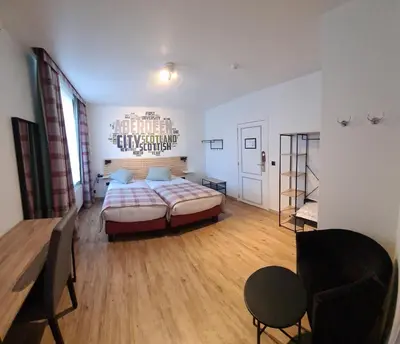 a bedroom with a bed and a chair in a room at Hotel La Roseraie in Wemmel
