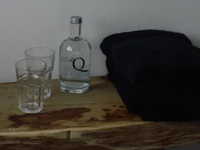 a bottle and two glasses on a wooden table at Quarante Cinq in Evergem
