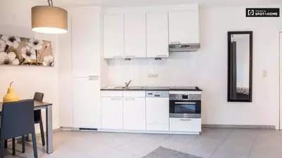 a kitchen with white cabinets and a table and a sink at Quartier des Quais Dansaert in Brussels