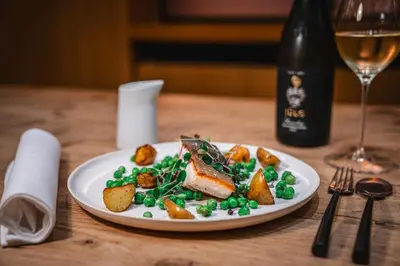 a plate of food on a table with a bottle of wine at Hotel Les Eleveurs in Halle