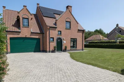 a brick house with a garage on a driveway at Villa De Ruiter in Waasmunster