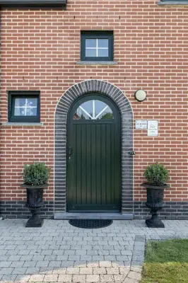 a green door on a brick building with two plants at Villa De Ruiter in Waasmunster