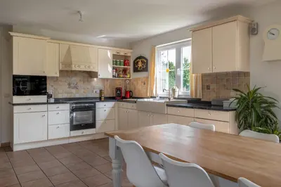 a kitchen with a wooden table and white cabinets at Villa De Ruiter in Waasmunster