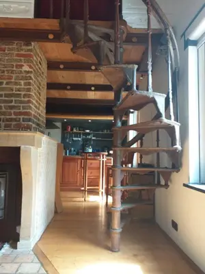 a wooden spiral staircase in a room with a kitchen at Villa Blanco in Opwijk