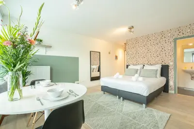a hotel room with a bed and a table and a dining room at SHWAY - The Card Room Green Studio in Antwerp