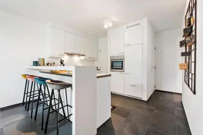 a kitchen with white cabinets and a counter with stools at Classy Apartment in City Center with Large Balcony in Ghent