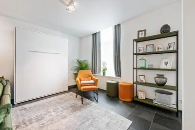a living room with an orange chair and a large mirror at Classy Apartment in City Center with Large Balcony in Ghent