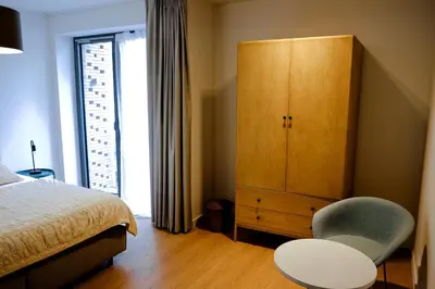 a bedroom with a bed and a chair and a cabinet at Modern Appartment in the Heart of Ghent in Ghent