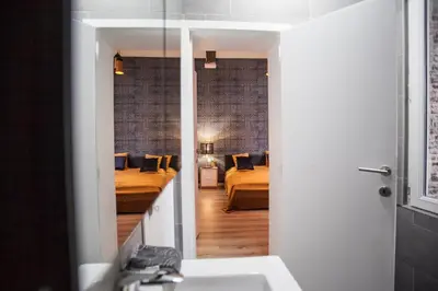 a bathroom with a sink and a bedroom with two beds at Luxury Suites Grotemarkt by Rikas Hotels in Antwerp
